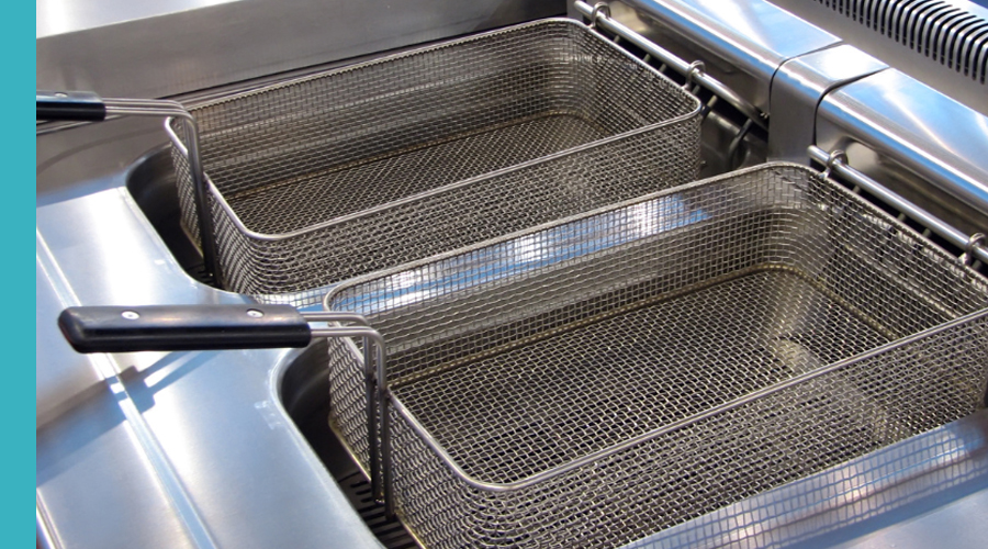 Close-up of commercial deep fryer baskets, highlighting their metal construction and placement in the fryer.