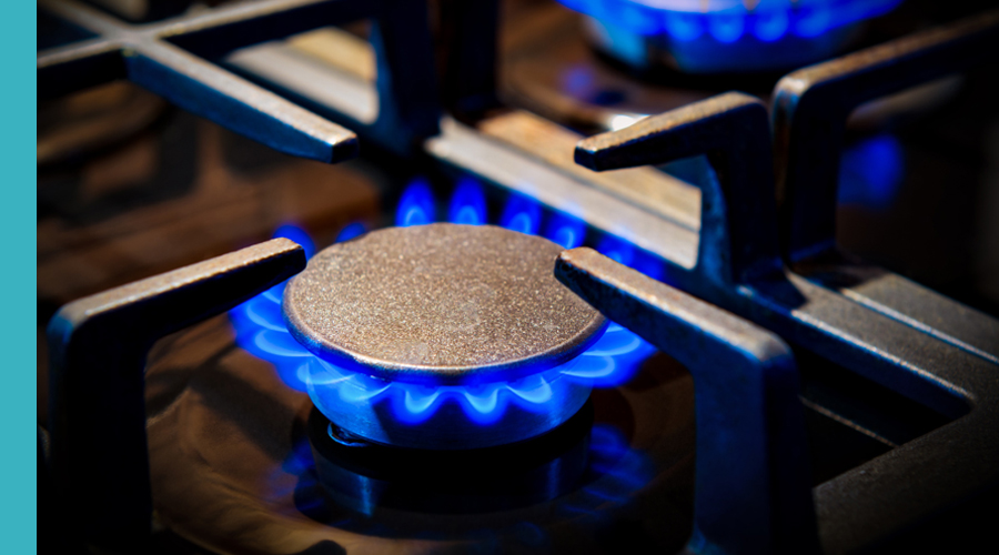 Close-up of a gas stove burner with blue flames igniting, emphasizing the stove's heating capability.